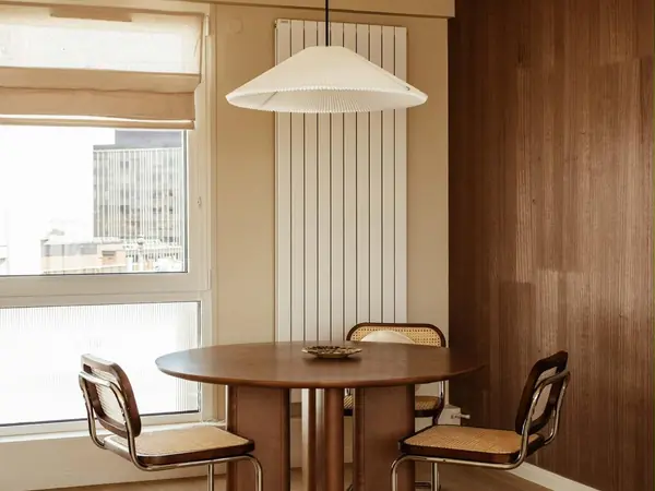 Coin repas avec table ronde, chaises cannées et suspension