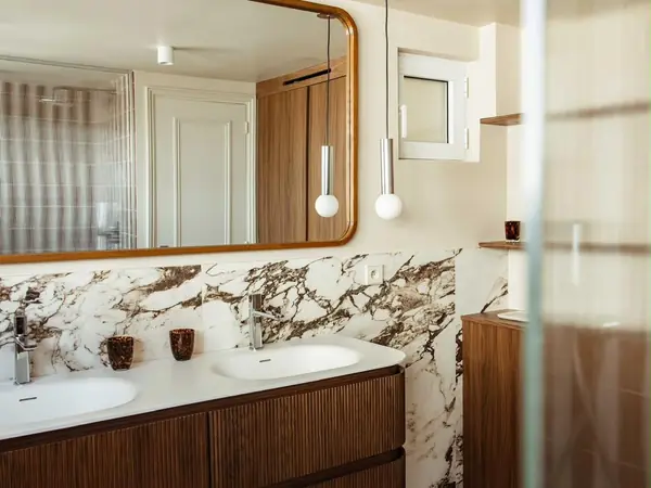 Salle de bain avec double vasque, crédence en marbre et miroir arrondi