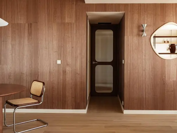 Séjour avec mur habillé de noyer, porte vitrée et chaises cannées