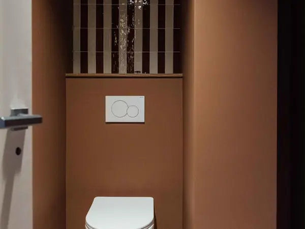WC suspendu sur mur couleur terre cuite et sol en marbre