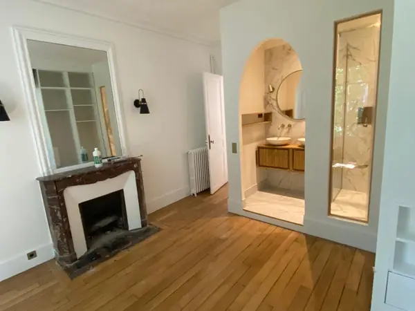 Chambre rénovée avec parquet, cheminée et salle d’eau