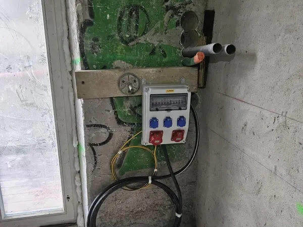 Coffret électrique de chantier avec prises, fixé au mur