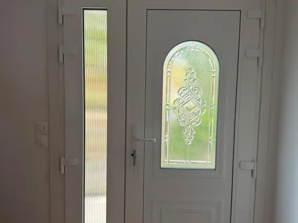 Porte d’entrée blanche avec vitrail et fixe latéral, vue de l’intérieur