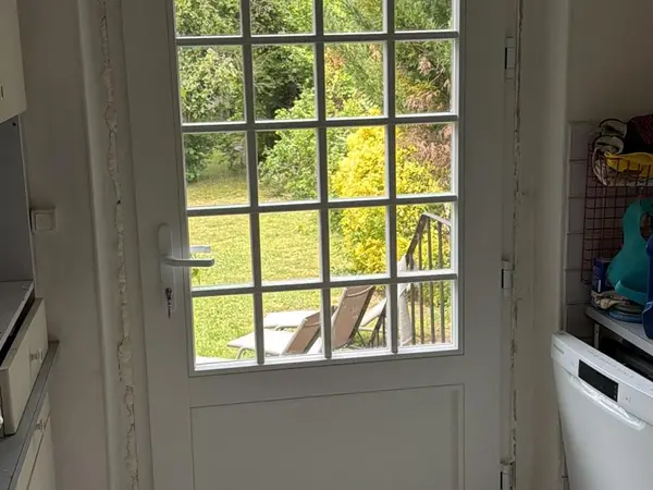 Porte vitrée blanche à petits carreaux entre la cuisine et le jardin