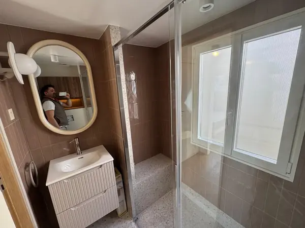 Salle d’eau avec miroir ovale et paroi vitrée