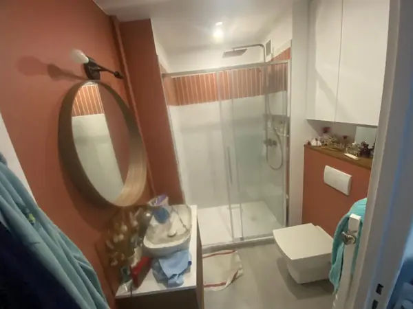 Salle d’eau avec miroir rond et douche à l’italienne