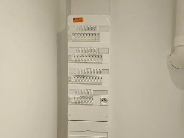 Tableau électrique blanc fermé, posé dans un couloir