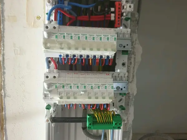 Tableau électrique ouvert en cours de raccordement, avec bornier de terre