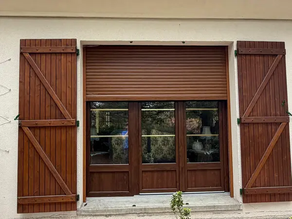 Volets battants en bois et volet roulant sur une baie vitrée